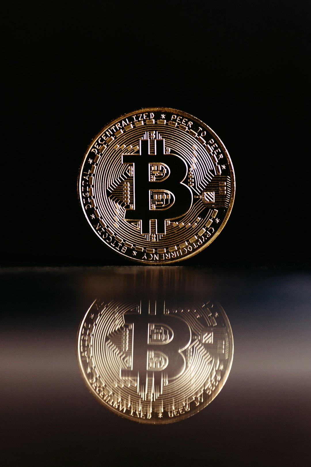 a bit coin sitting on top of a reflective surface