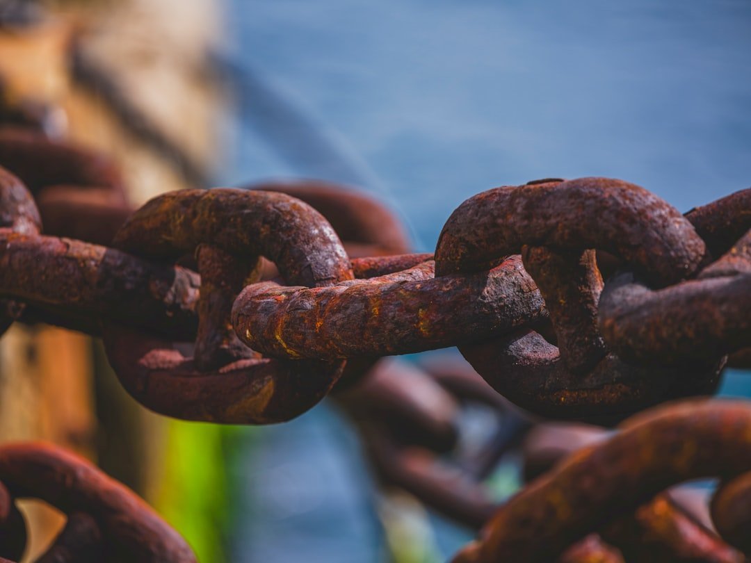 Close-up of a rusty metal chain with water background